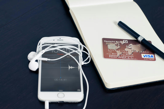 credit card on a notepad with a pen and a phone with headset